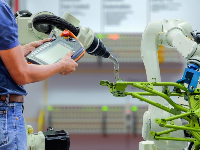 82312775 - engineers use a wireless remote control of robotic welding and robot workpiece for smart factory, industry 4.0 concept
